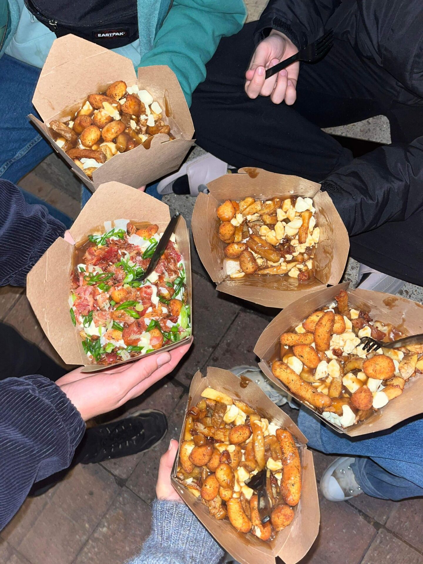 5 plats de poutines tenus dans les mains