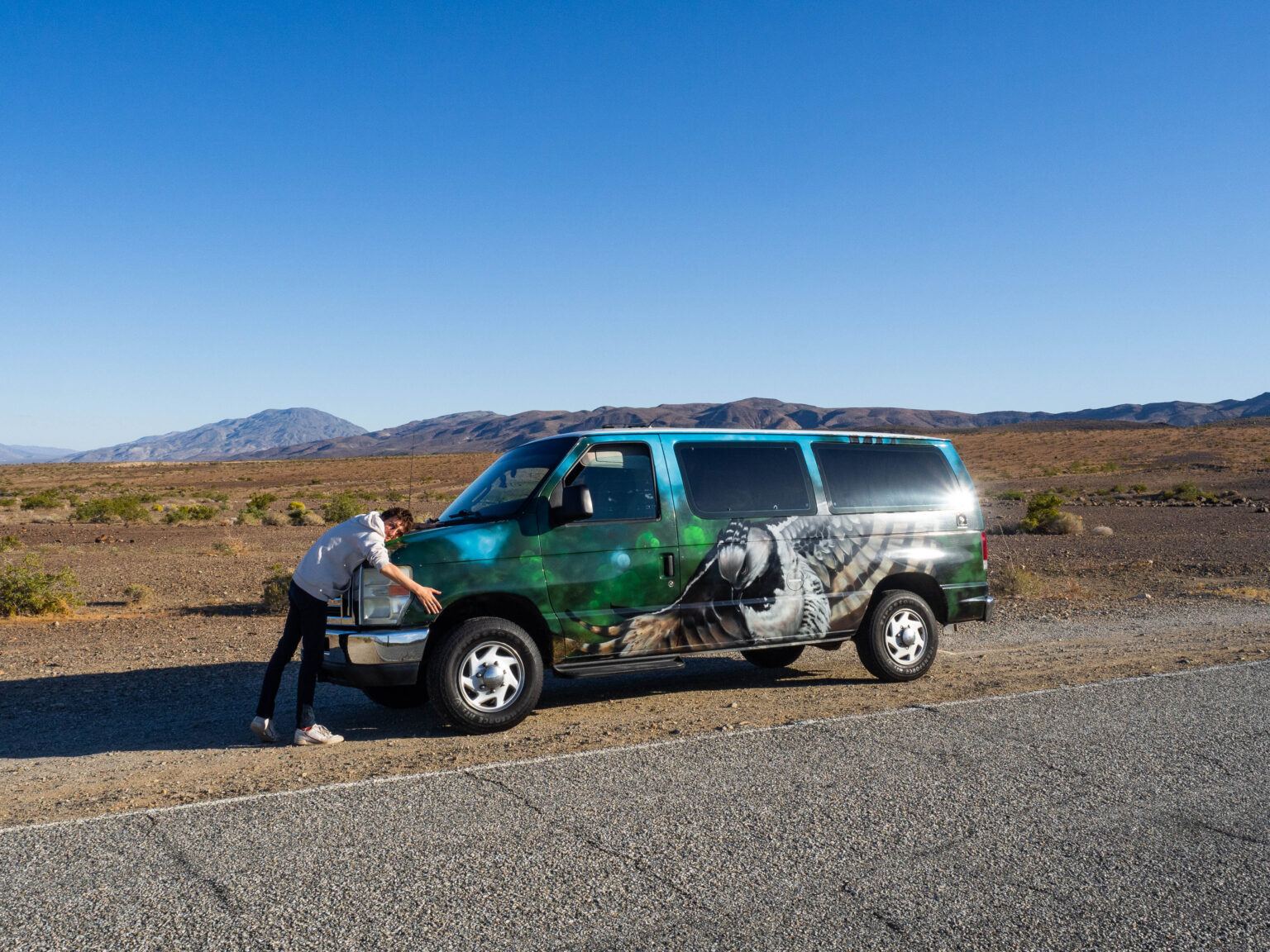 theo qui fait un calin à un van aménagé sur le bord d'une route en plein milieu du désert