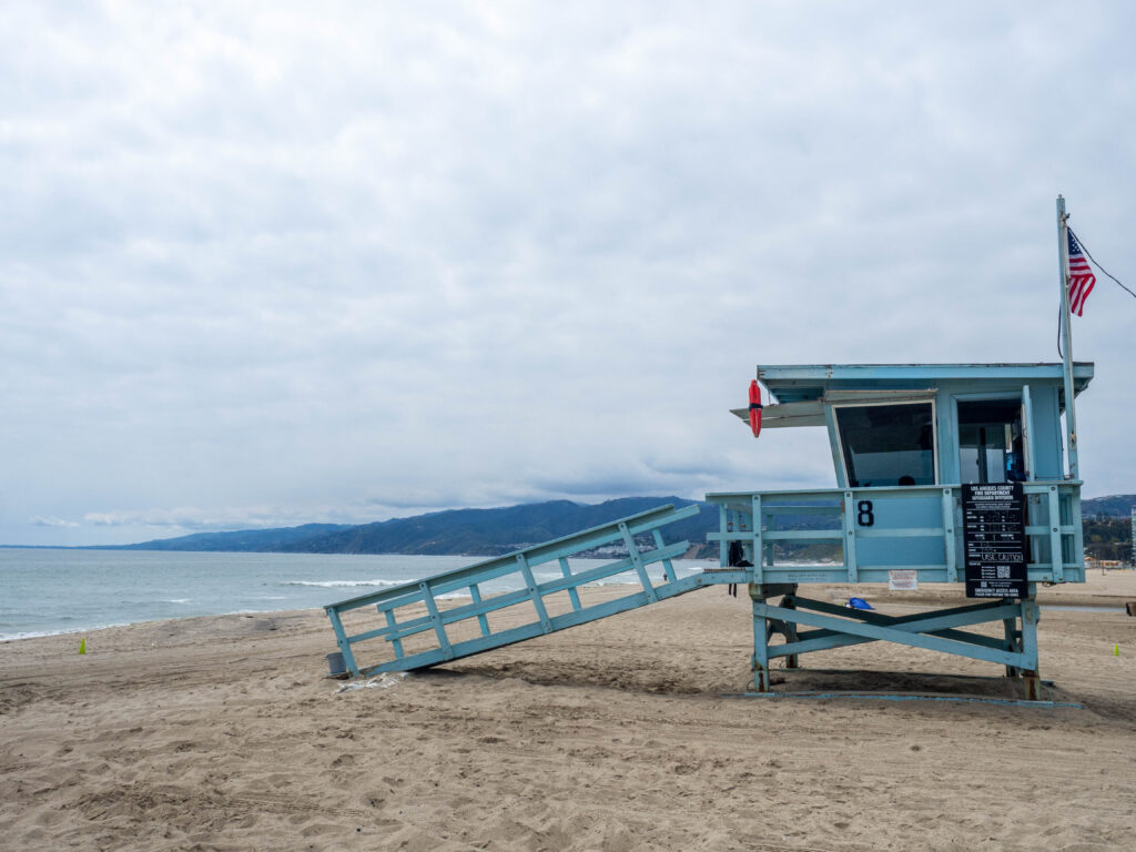 cabane de sauveteur sur une plage et on voit la mer et des collines en fond